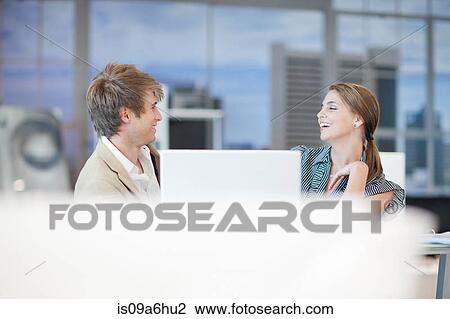 Stock Image - Business people talking at desk. Fotosearch