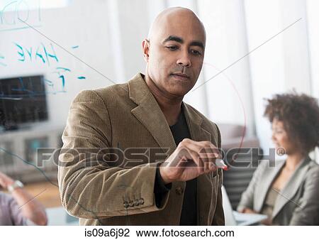 Stock Image - Businessman drawing graph in meeting. Fotosearch