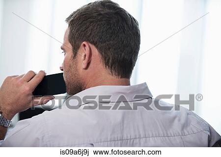 Businessman holding cell phone in office View Large Photo Image Stock Image - Businessman holding cell phone in office. Fotosearch