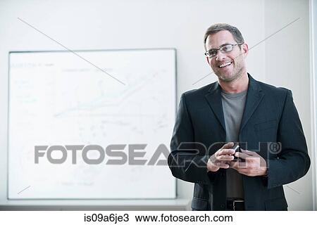 Stock Image - Businessman holding cell phone in office. Fotosearch