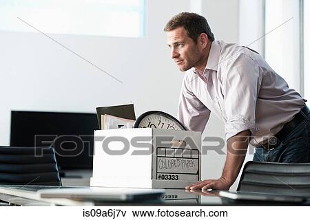 Stock Photo - Businessman packing up box in office. Fotosearch