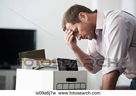 Stock Photo - Businessman packing up box in office. Fotosearch
