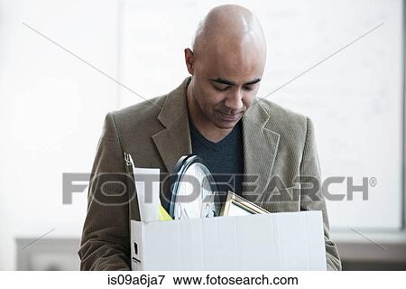 Businessman packing up box in office View Large Photo Image Stock Photo - Businessman packing up box in office. Fotosearch