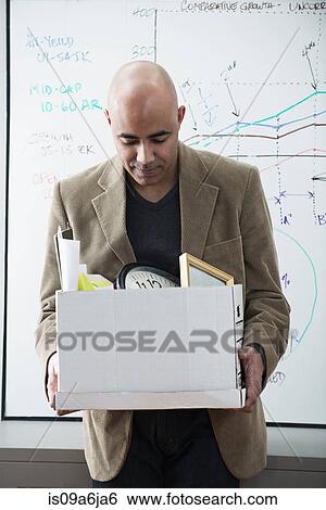 Stock Photograph - Businessman packing up box in office. Fotosearch