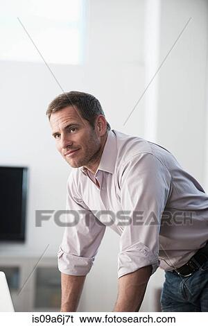 Stock Photograph - Businessman standing at desk. Fotosearch