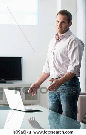 Businessman standing at desk View Large Photo Image Stock Photograph - Businessman standing at desk. Fotosearch