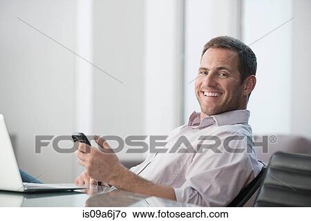 Businessman using cell phone at desk View Large Photo Image Picture - Businessman using cell phone at desk. Fotosearch