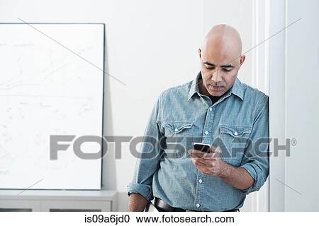 Stock Image - Businessman using cell phone in office. Fotosearch
