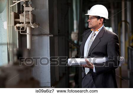 Stock Photo - Businessman with blueprints in plant. Fotosearch