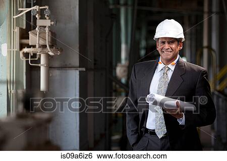 Stock Photograph - Businessman with blueprints in plant. Fotosearch