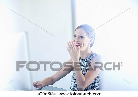 Stock Photograph - Businesswoman laughing at desk. Fotosearch