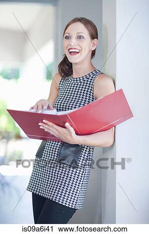 Stock Image - Businesswoman reading folder in office. Fotosearch