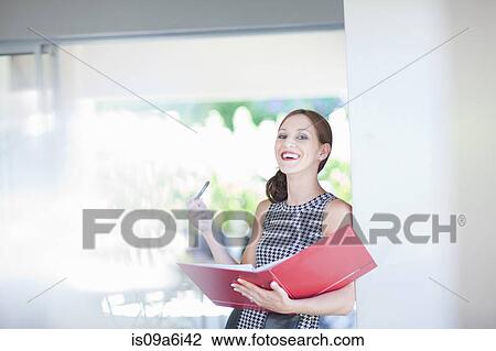 Stock Image - Businesswoman reading folder in office. Fotosearch
