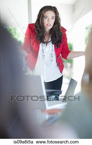Stock Image - Businesswoman shrugging in meeting. Fotosearch
