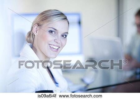 Stock Image - Businesswoman smiling at desk. Fotosearch
