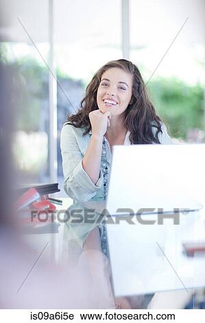 Stock Image - Businesswoman talking at desk. Fotosearch