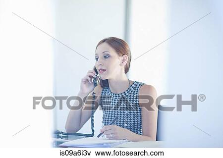 Stock Photo - Businesswoman talking on phone at desk. Fotosearch