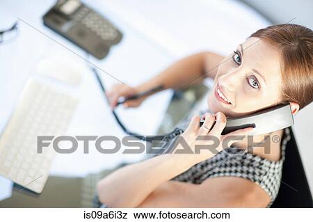 Stock Photo - Businesswoman talking on phone at desk. Fotosearch