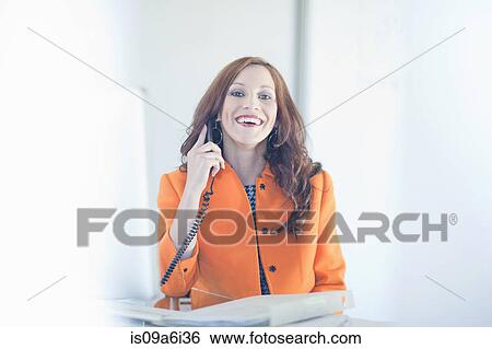 Stock Photograph - Businesswoman talking on phone at desk. Fotosearch
