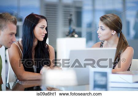 Stock Image - Businesswoman talking to couple at desk. Fotosearch