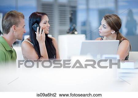 Stock Image - Businesswoman talking to couple at desk. Fotosearch