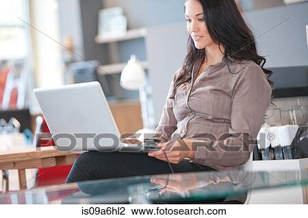 Stock Image - Businesswoman using laptop at desk. Fotosearch