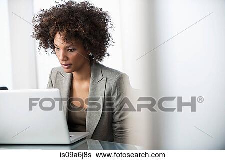 Stock Photograph - Businesswoman using laptop at desk. Fotosearch
