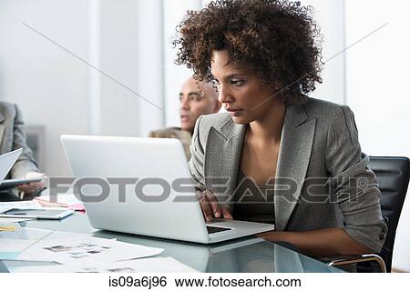 Stock Photograph - Businesswoman using laptop in meeting. Fotosearch