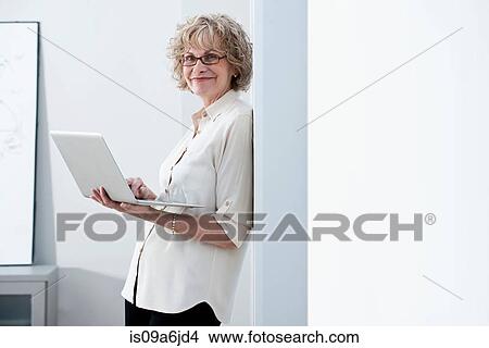 Picture - Businesswoman using laptop in office. Fotosearch