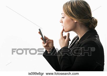 Businesswoman using smartphone as mirror View Large Photo Image Stock Photography - Businesswoman using smartphone as mirror. Fotosearch