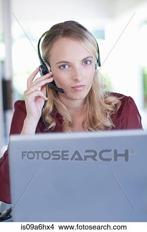 Picture - Businesswoman wearing headset at desk. Fotosearch