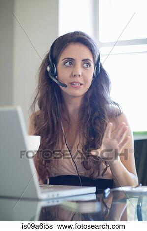 Businesswoman wearing headset at desk View Large Photo Image Stock Photograph - Businesswoman wearing headset at desk. Fotosearch