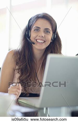 Businesswoman wearing headset at desk View Large Photo Image Stock Photograph - Businesswoman wearing headset at desk. Fotosearch