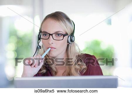 Stock Photography - Businesswoman wearing headset at desk. Fotosearch