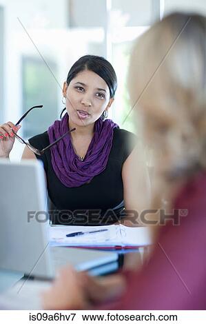 Stock Photo - Businesswomen talking at desk. Fotosearch