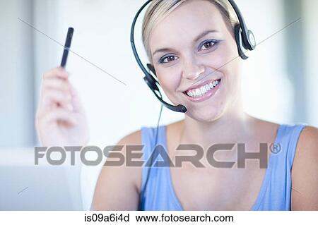Stock Image - Businesswomen wearing headset at desk. Fotosearch