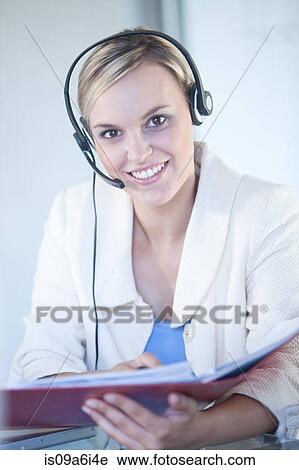 Stock Image - Businesswomen wearing headset at desk. Fotosearch