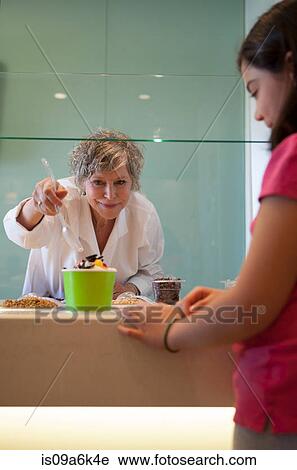 Cashier putting toppings on yogurt View Large Photo Image Stock Image - Cashier putting toppings on yogurt. Fotosearch