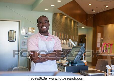 Stock Image - Cashier smiling behind counter. Fotosearch