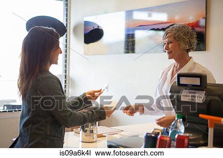 Stock Image - Cashier talking to customer in store. Fotosearch