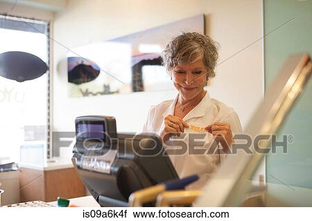 Stock Image - Cashier wearing uniform in store. Fotosearch