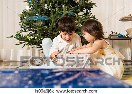 Stock Image - Children opening Christmas gifts. Fotosearch