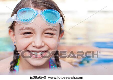 Stock Image - Close up of girl wearing goggles in pool. Fotosearch