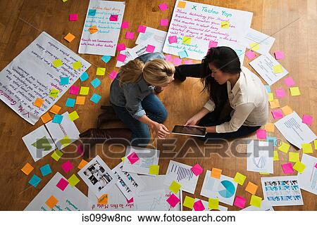 Colleagues sitting on floor with digital tablet, papers and adhesive notes View Large Photo Image Stock Image - Colleagues sitting on floor with digital tablet, papers and adhesive notes. Fotosearch