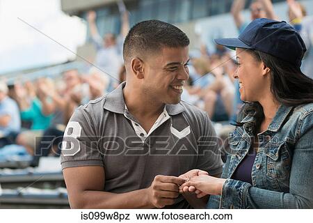 Stock Photo - Couple getting engaged at sports game. Fotosearch