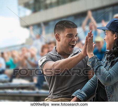 Couple high-fiving at sports game View Large Photo Image Stock Photograph - Couple high-fiving at sports game. Fotosearch