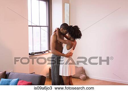 Stock Image - Couple hugging in living room. Fotosearch