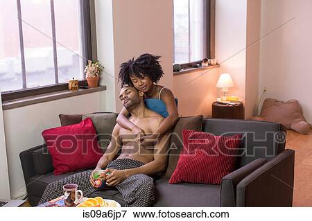 Stock Photo - Couple hugging on sofa in living room. Fotosearch