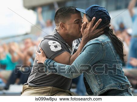 Couple kissing at sports game View Large Photo Image Stock Photograph - Couple kissing at sports game. Fotosearch