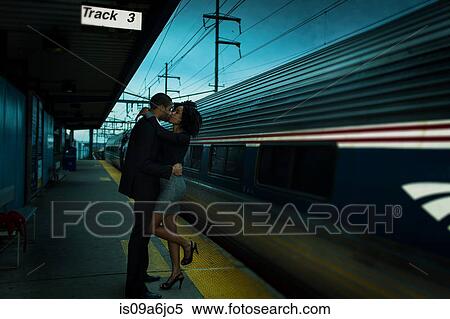 Stock Photography - Couple kissing at train station. Fotosearch
